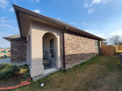 Side of a brick home with a white seamless gutter and downspout