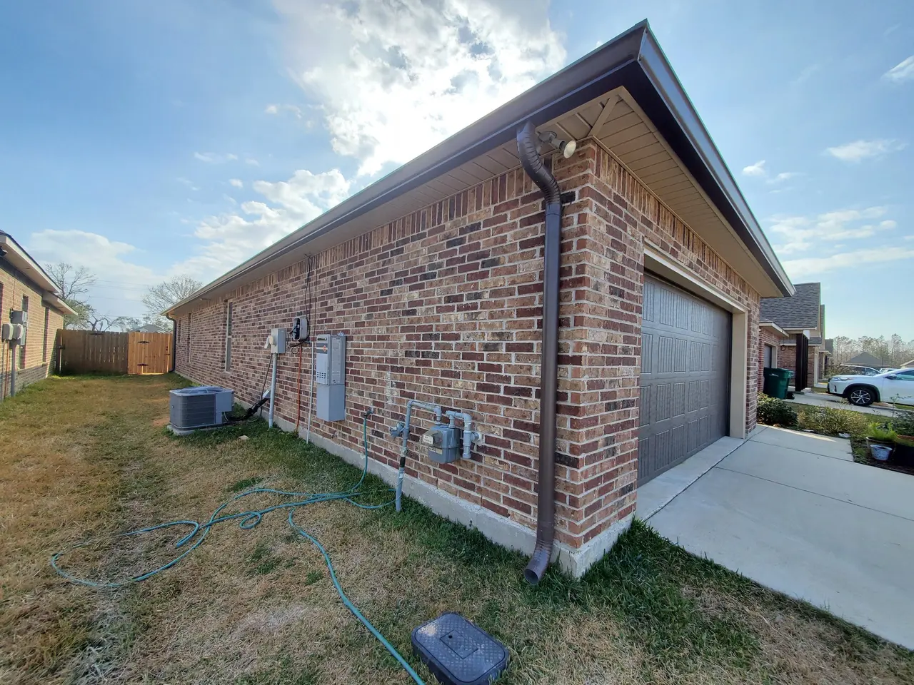 Brick garage side with a new white downspout