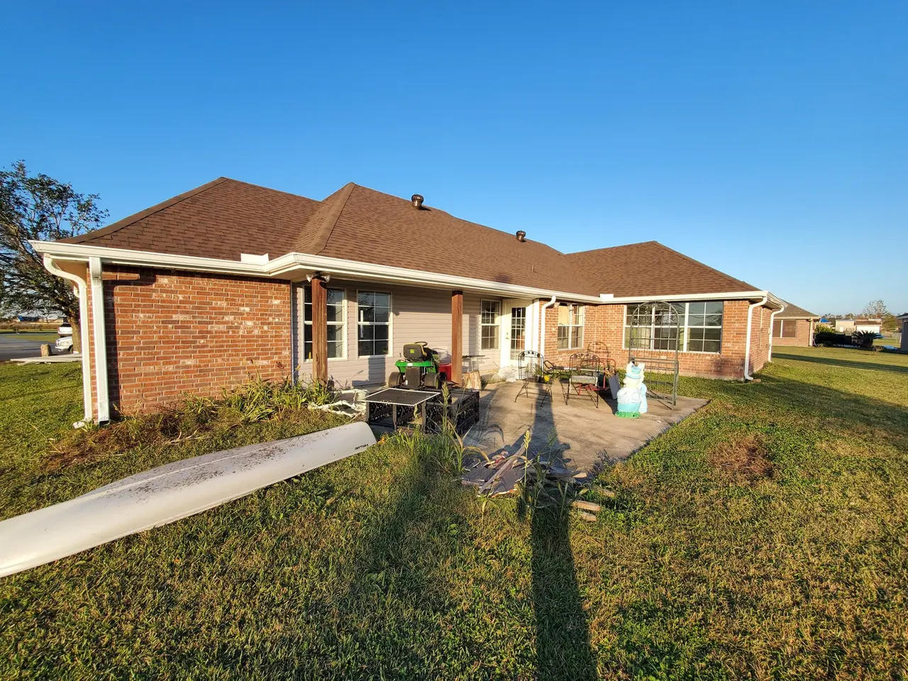 Brick ranch with a coil of seamless gutter on the lawn during install