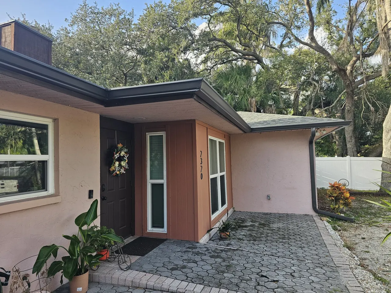 Front entry of a stucco home with new bronze gutters