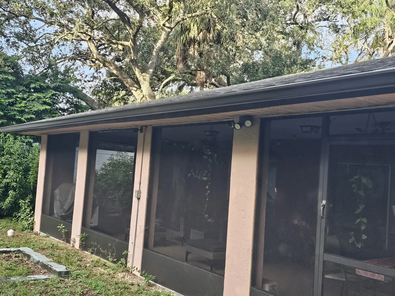Screened patio with new bronze gutters under oak trees