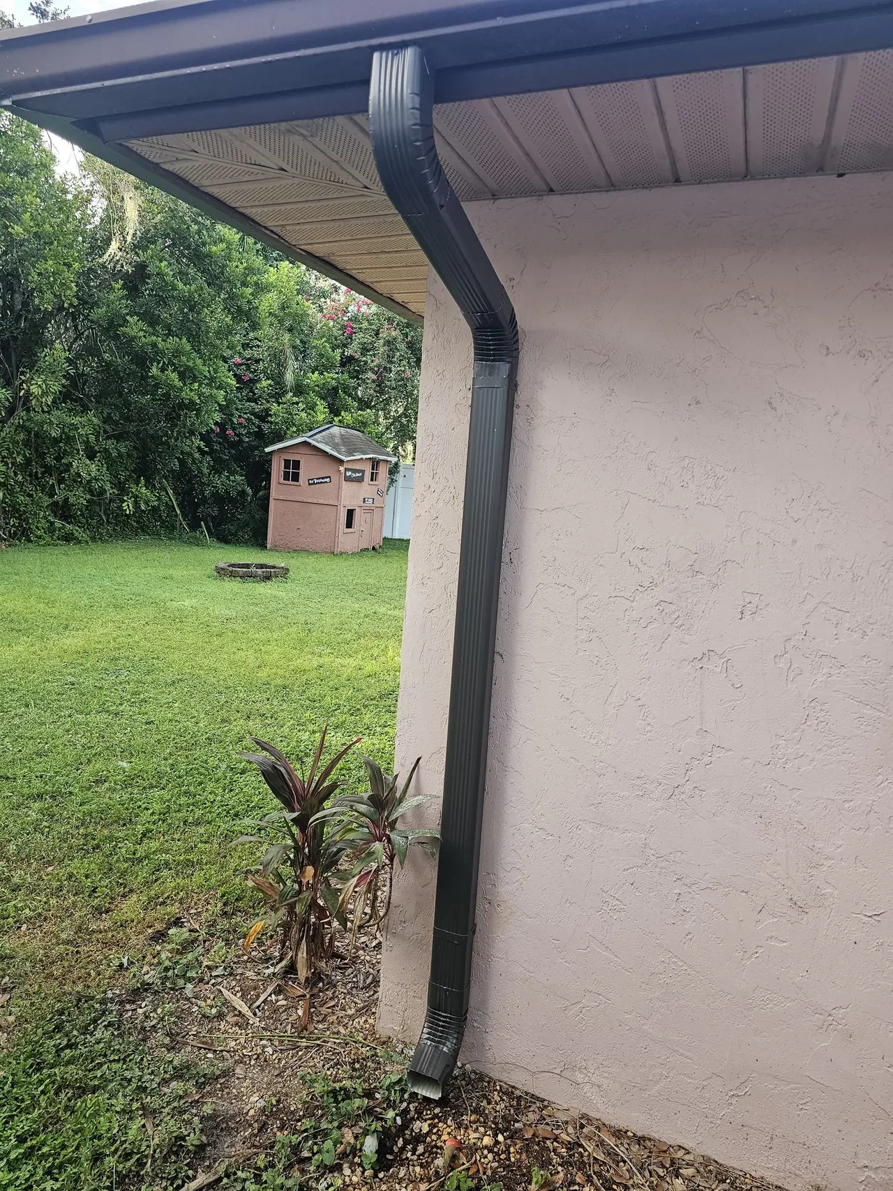 Bronze downspout and extension on a stucco corner