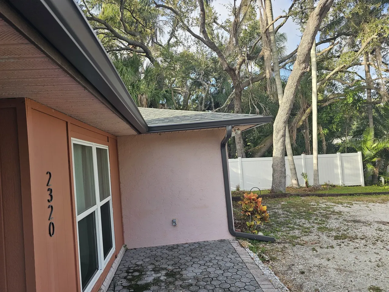 Bronze gutter on a stucco home with the house number by the door