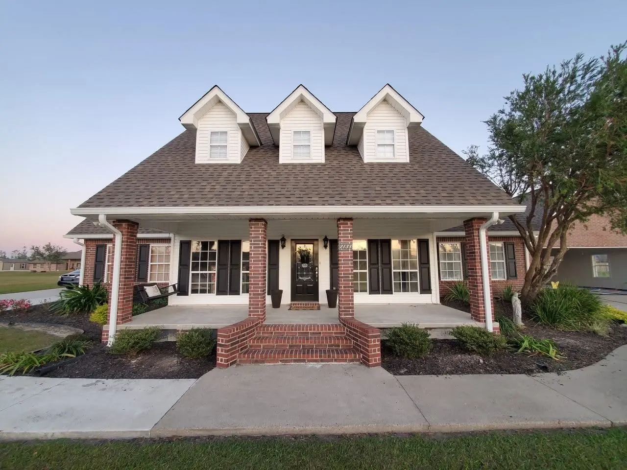 Gray colonial with dormers and brick porch columns, new gutters