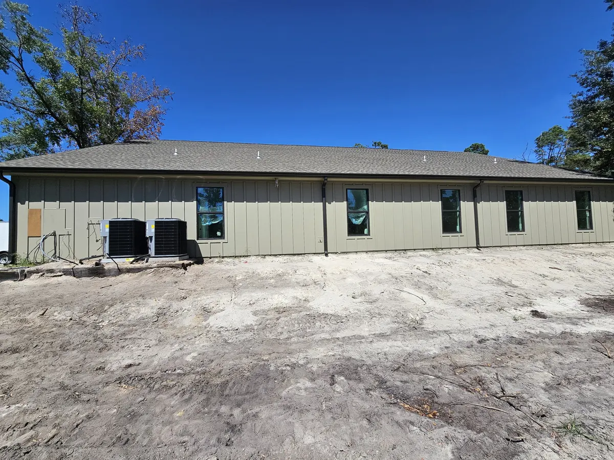 Long single-story commercial building with new gutters on a sandy lot