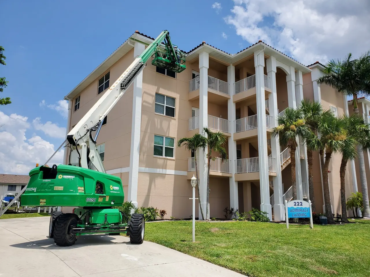 Four-story condo building with a boom lift installing gutters