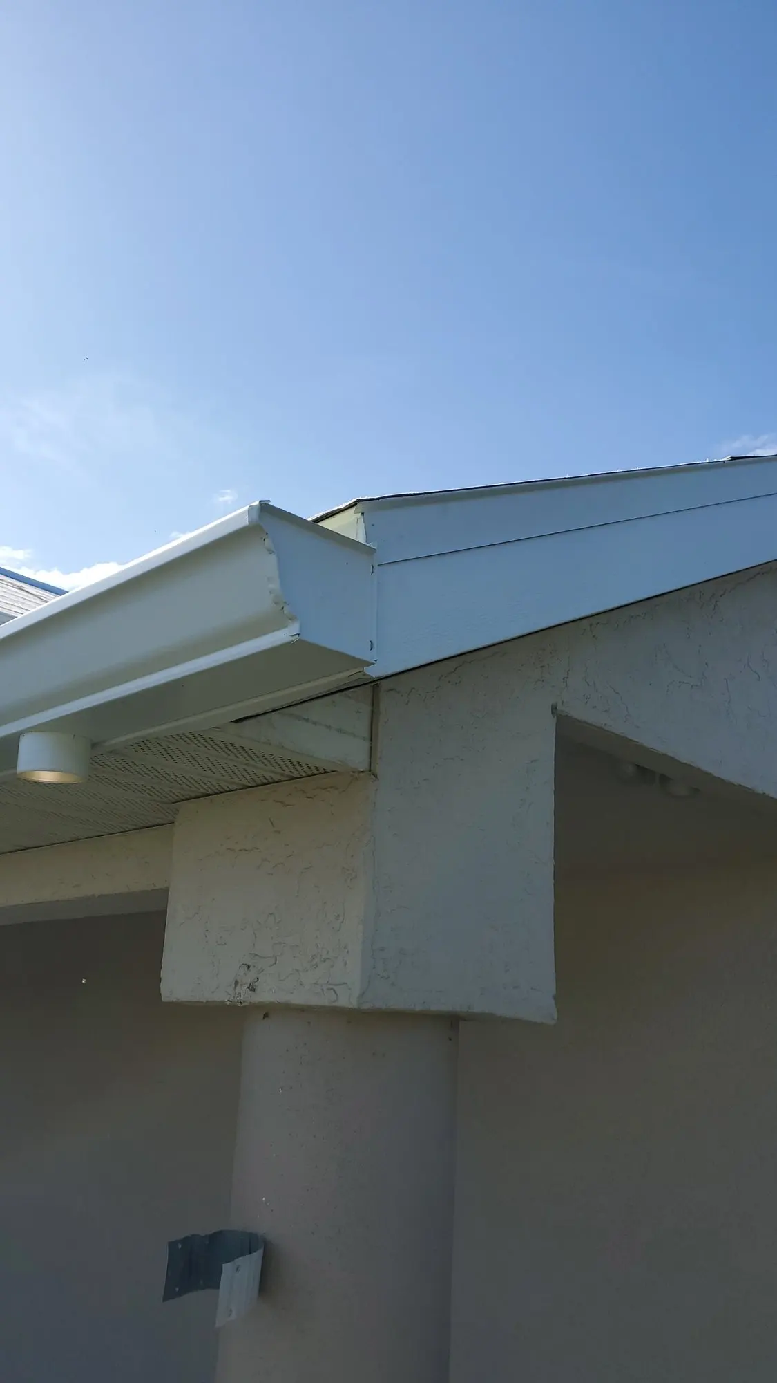 White gutter corner on a white stucco wall