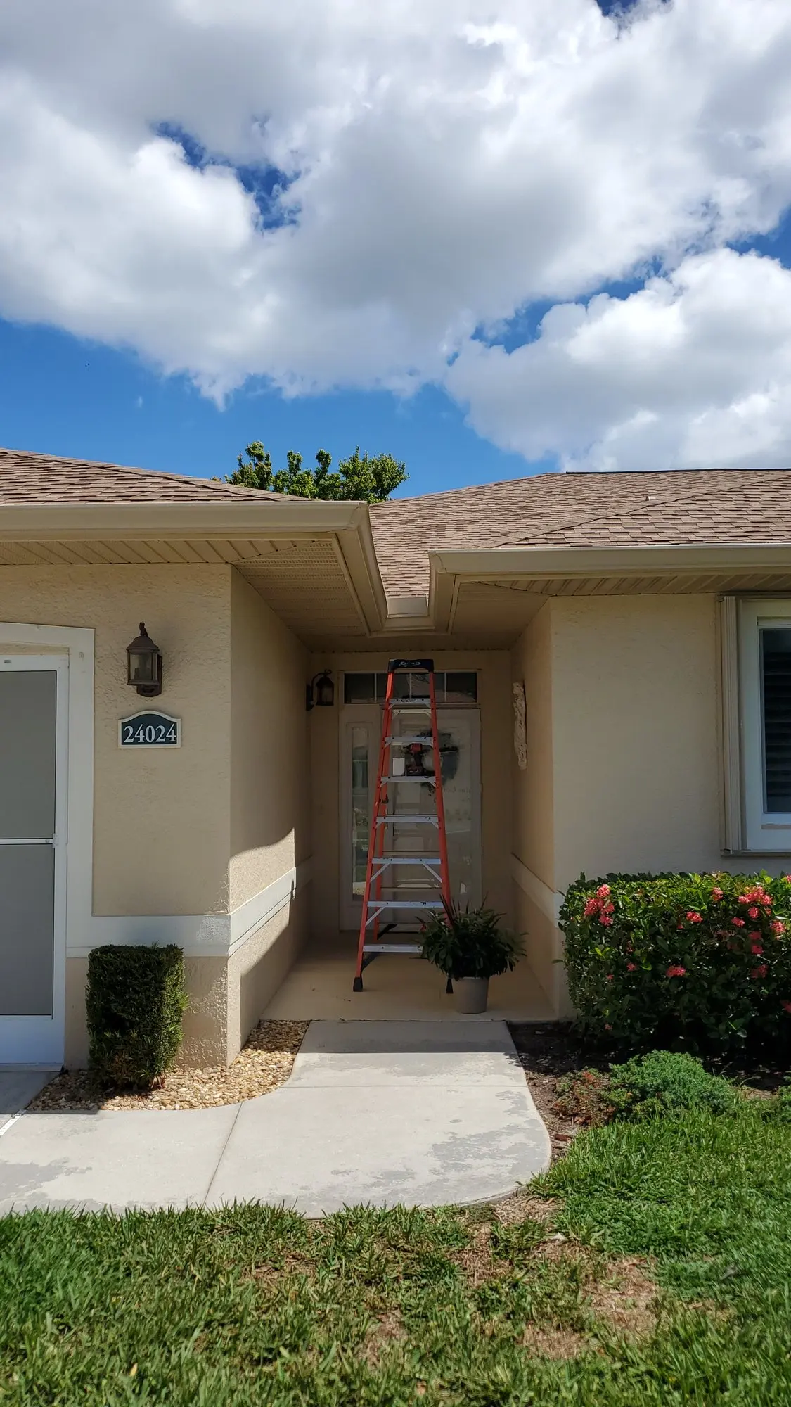 Ladder at the entry of a stucco home during a gutter install