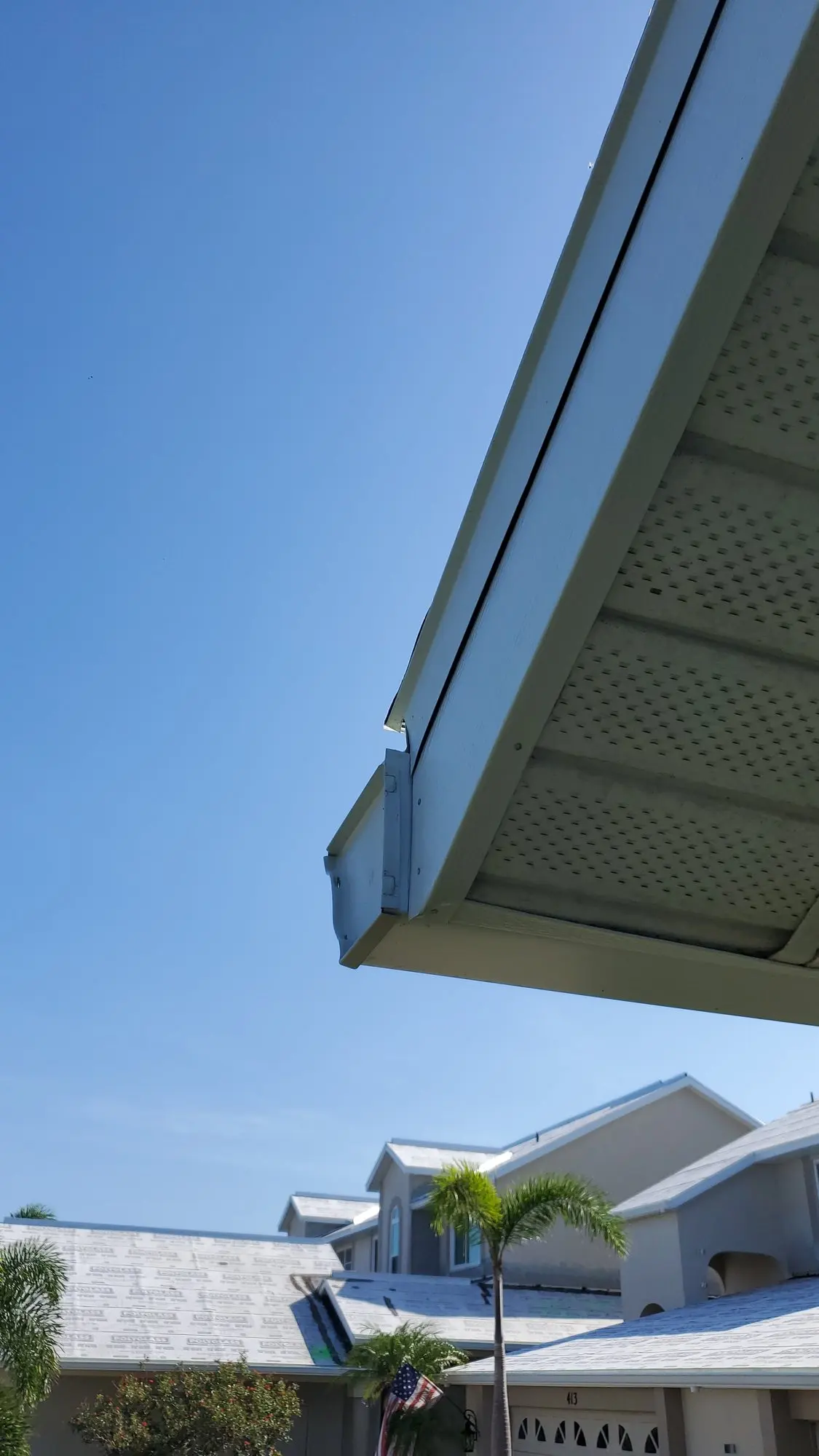 Long white gutter run along a roofline with a downspout
