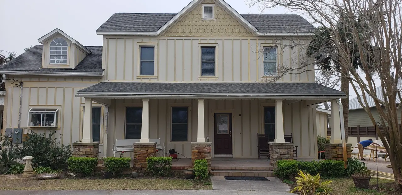Two-story cream farmhouse with new white gutters and a wide porch