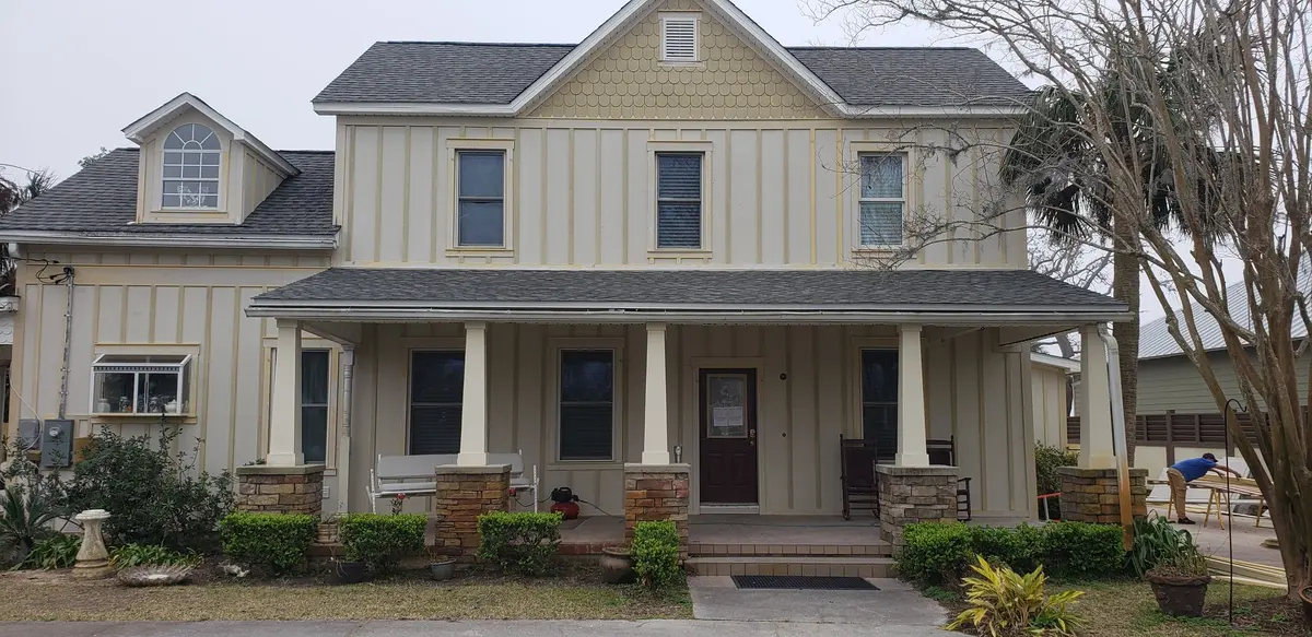 Two-story cream farmhouse with new white gutters and a wide porch