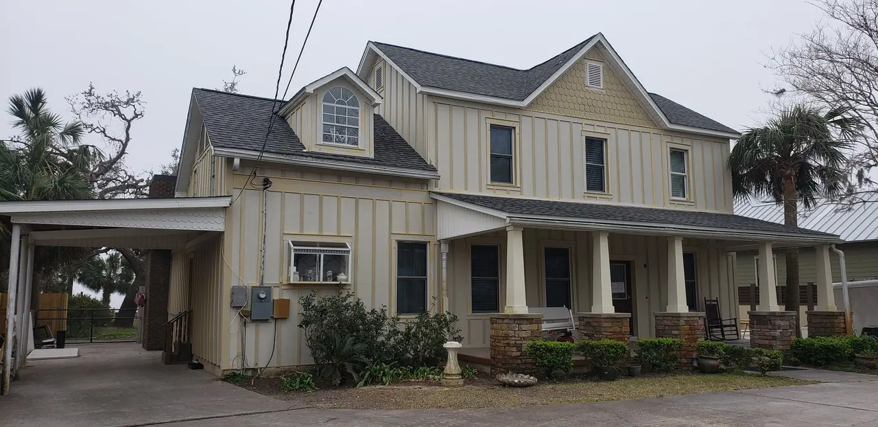 Two-story farmhouse with new gutters and a carport