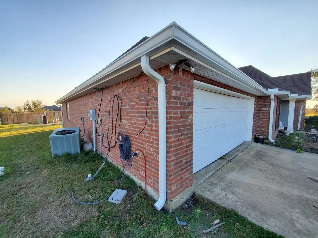 Brick home at sunset with new white gutters and a corner downspout
