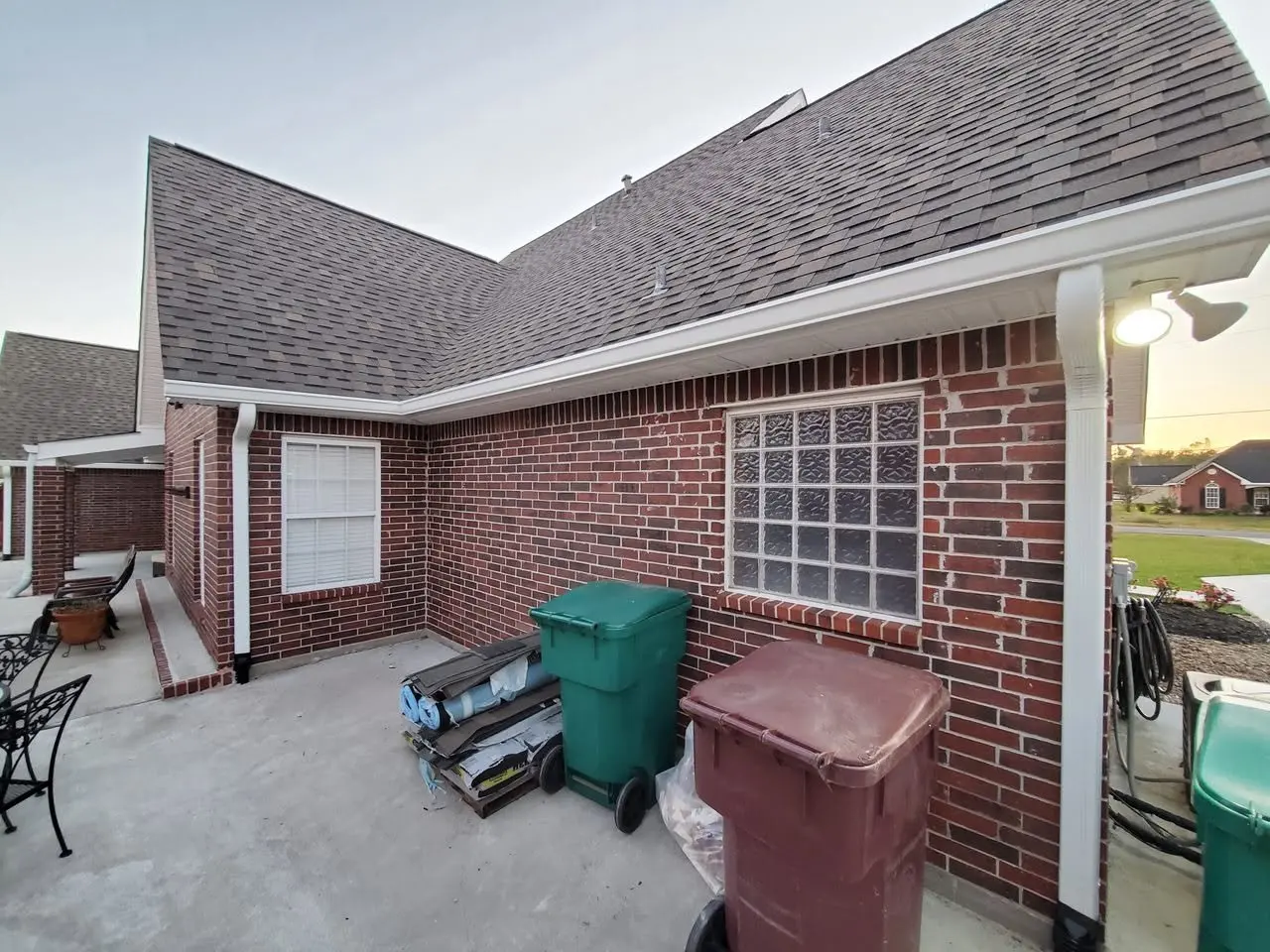 Rear of a brick home with white gutters above a glass-block window