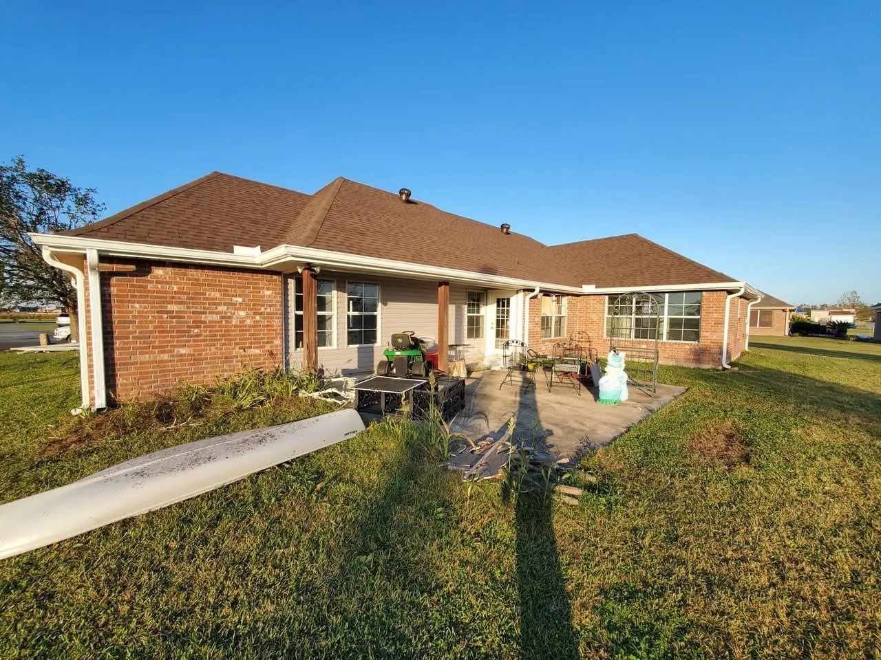 Rear of a brick ranch with white gutters along the patio roof