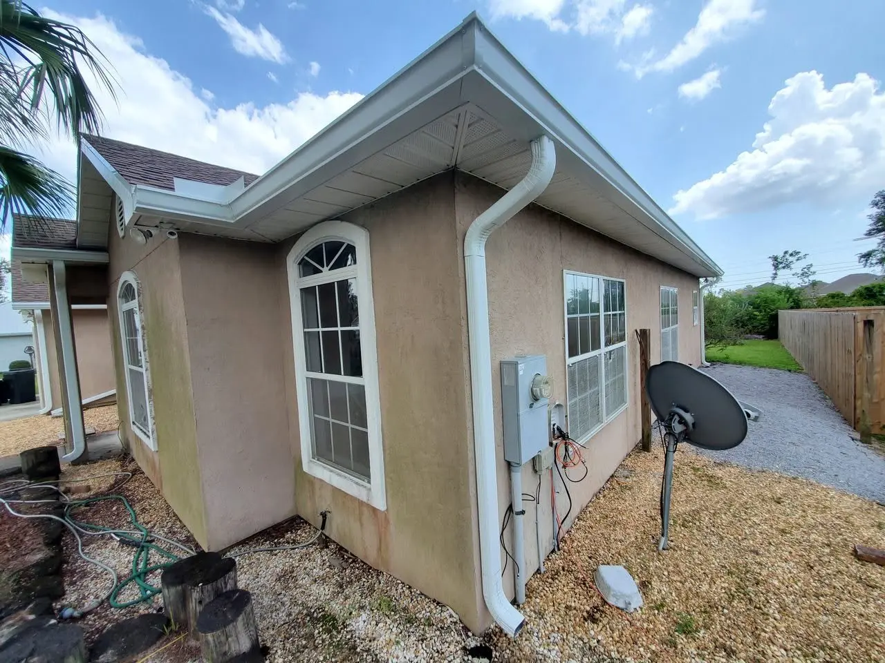Stucco home with white gutters and a downspout next to the utility meter