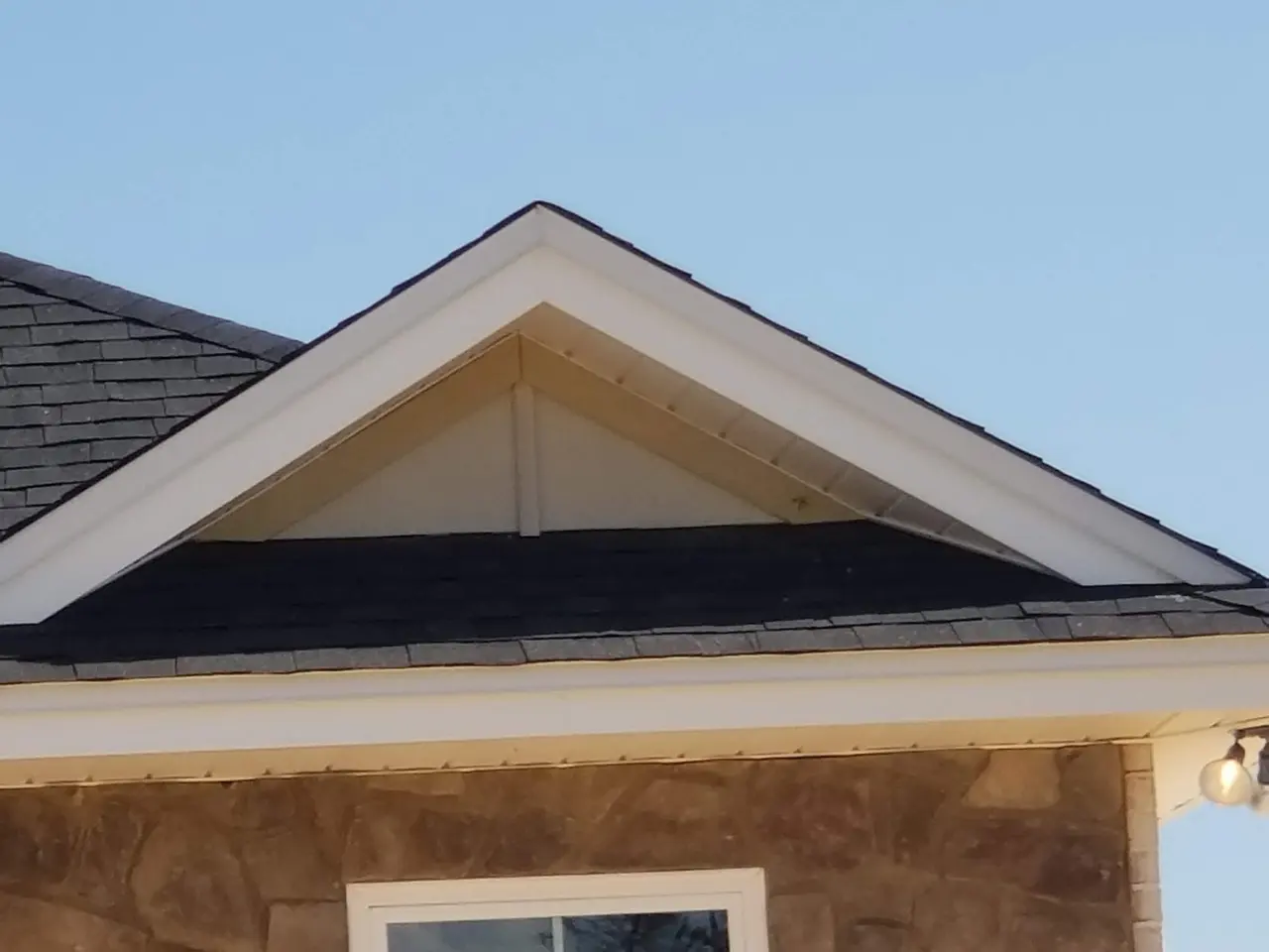 Gable end of a stucco home with a new white gutter along the eave