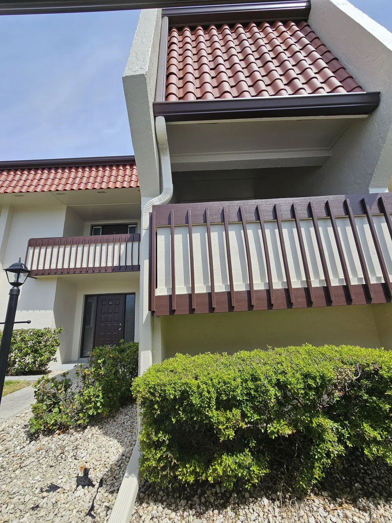 Brown gutter on a tile-roof corner above a striped awning