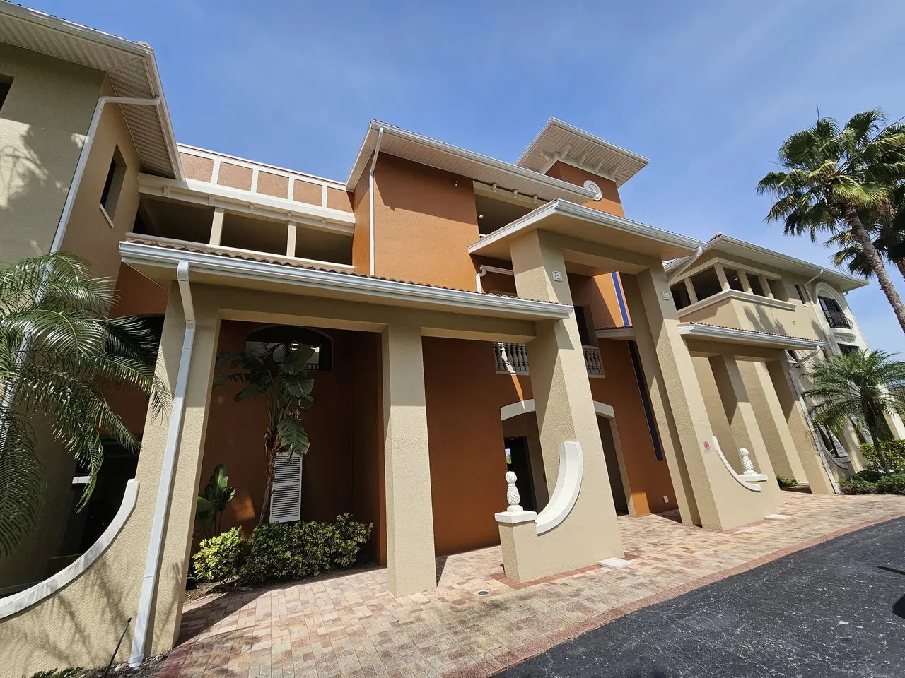 White seamless gutters along the roofline of a three-story stucco building with columns