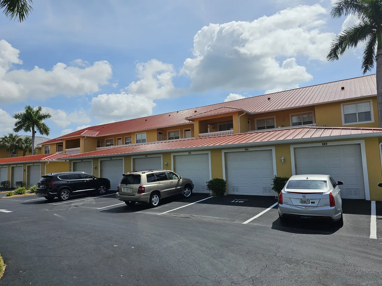 Row of garages with a red metal roof and new white gutters