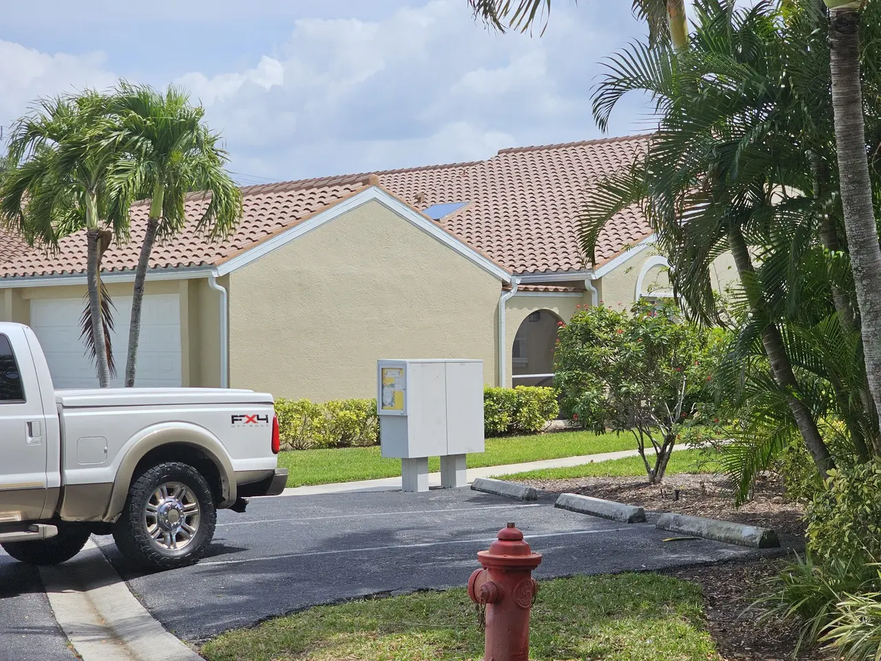 Tile-roof building with new white gutters, palms, and a fire hydrant out front