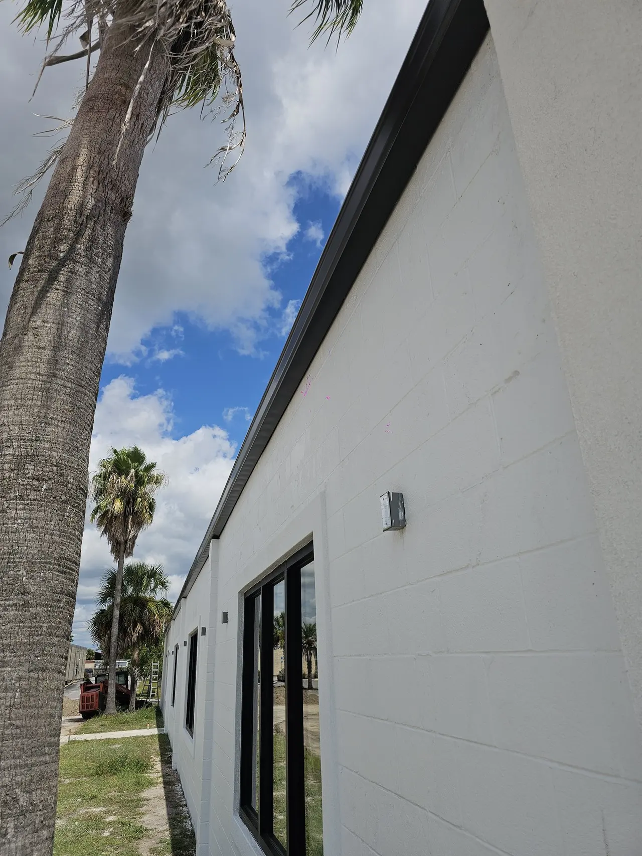 White modern home with black gutters against a blue sky