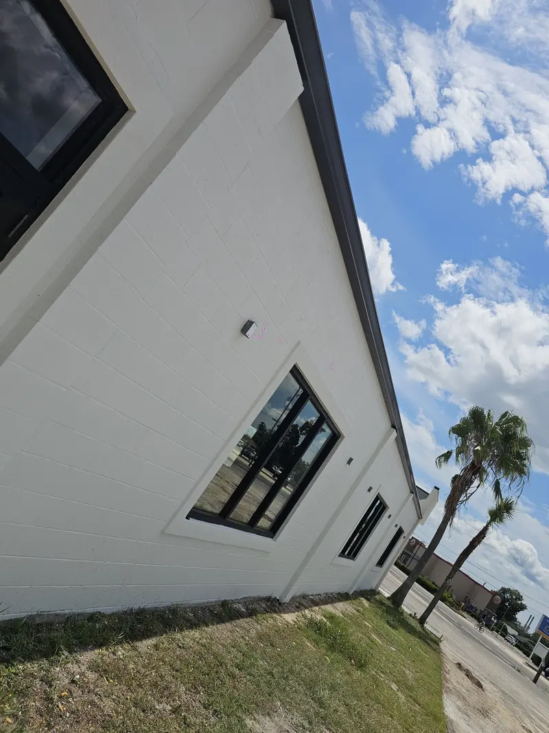 Corner of a white modern home with black gutters and a downspout