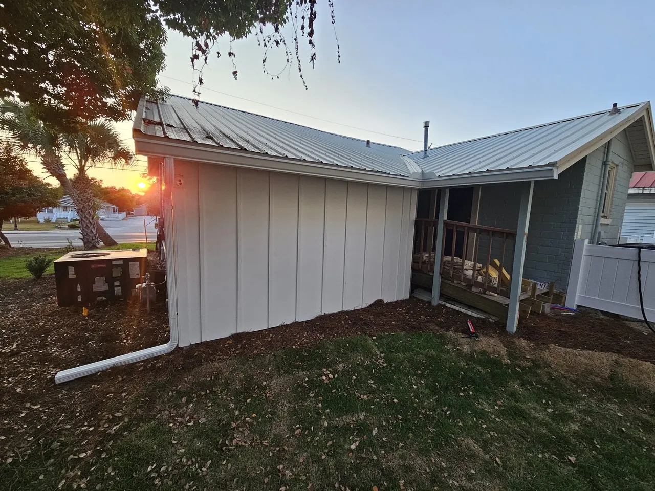 New home with a metal roof and white gutters at sunset