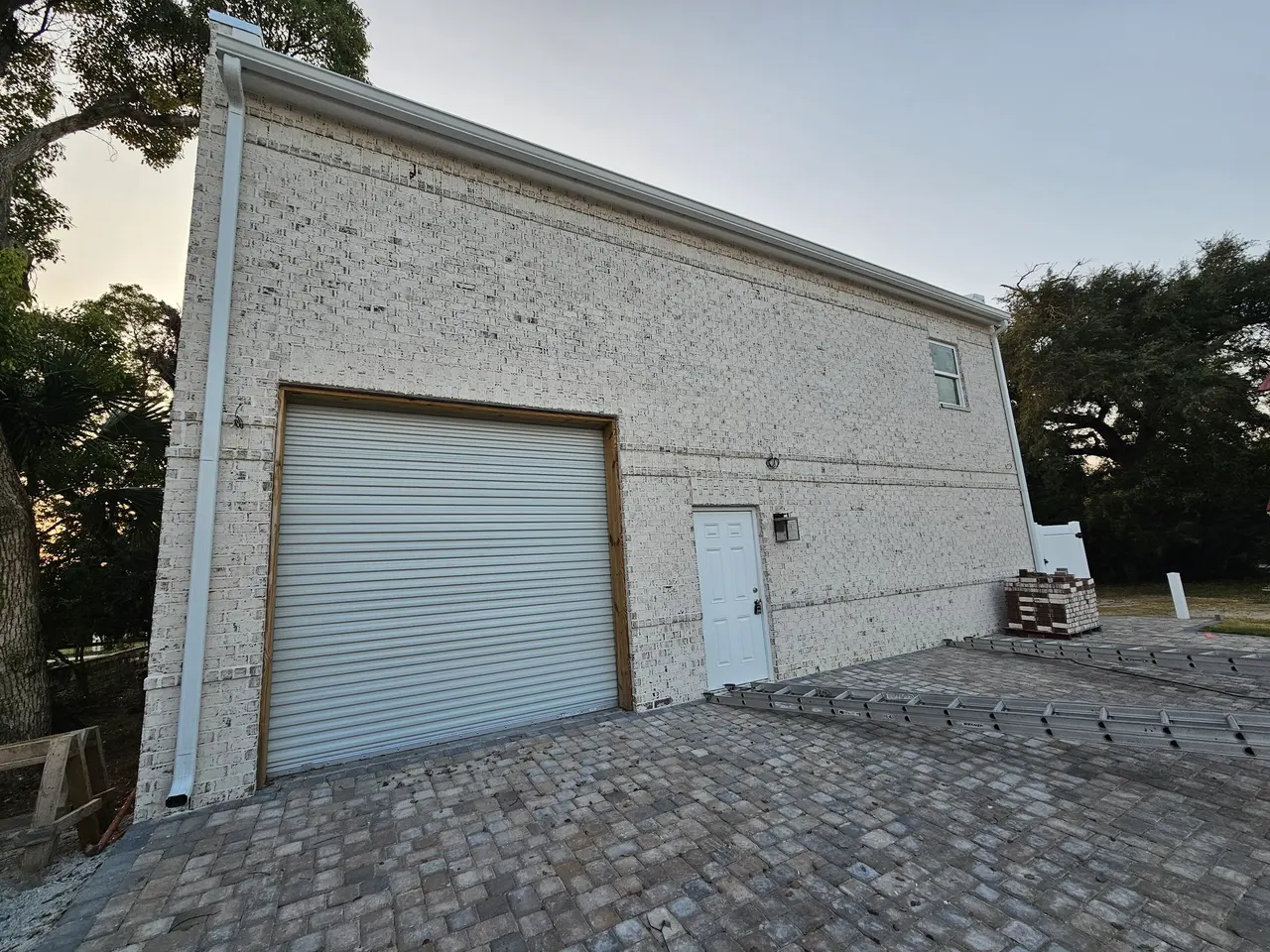 New garage with white gutters and a paver driveway