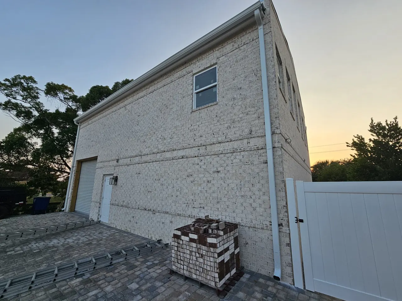 Two-story new build with white gutters and a white vinyl fence