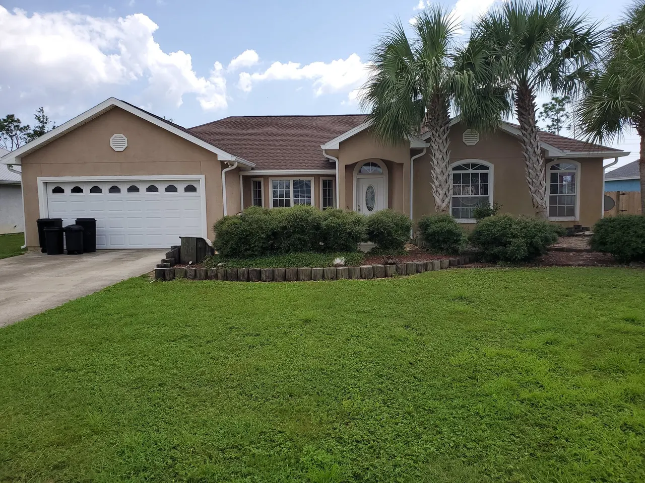Tan Florida ranch home with palm trees and new white gutters
