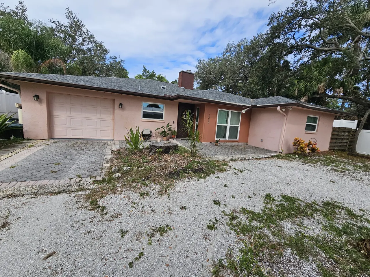 Pink stucco ranch with bronze gutters under oak trees