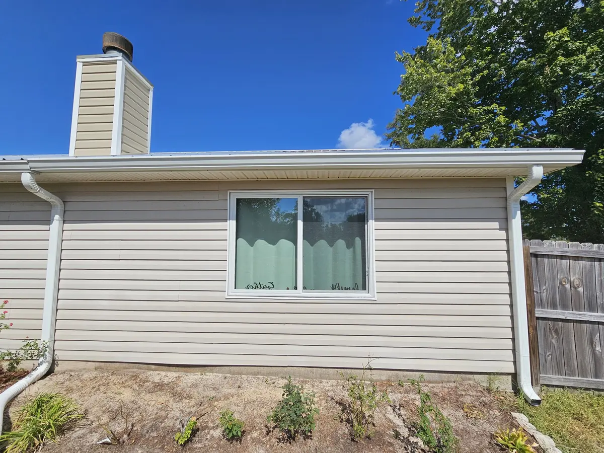 Front of a siding home with white seamless gutters and a chimney