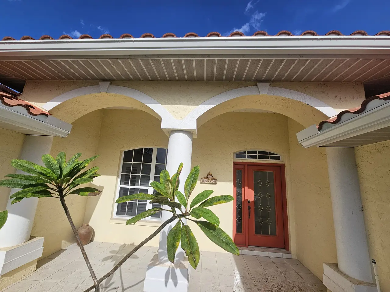 Arched front entry of a tile-roof home with new gutters