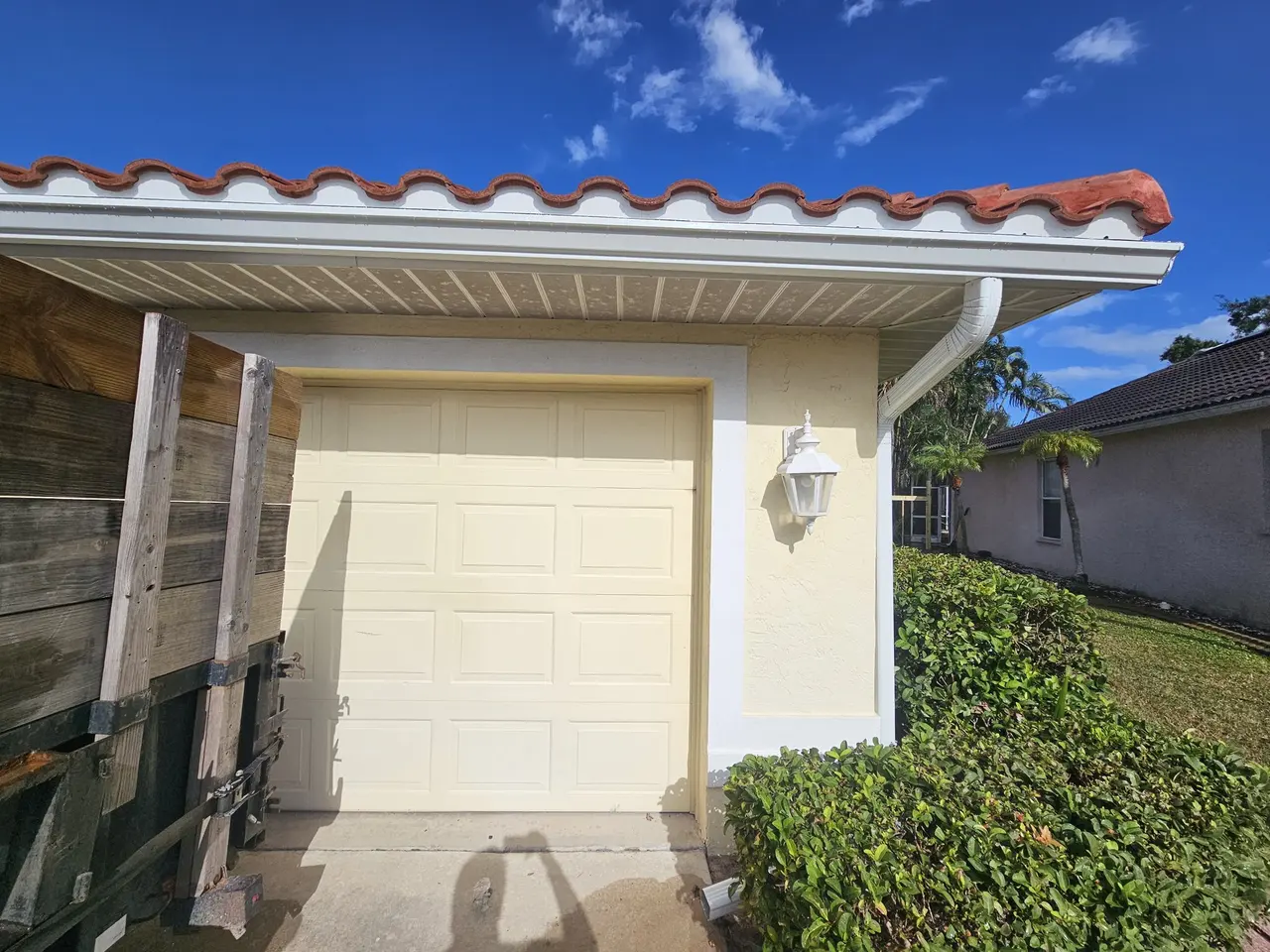 Garage side of a tile-roof home with white gutter and downspout